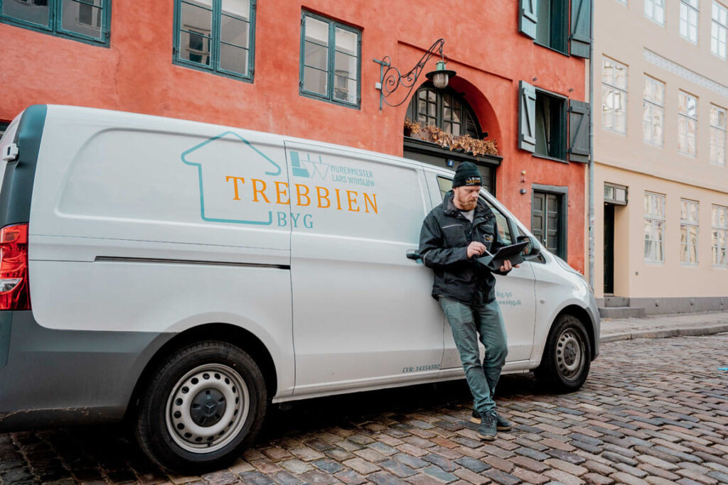 mand med tablet foran firmabil